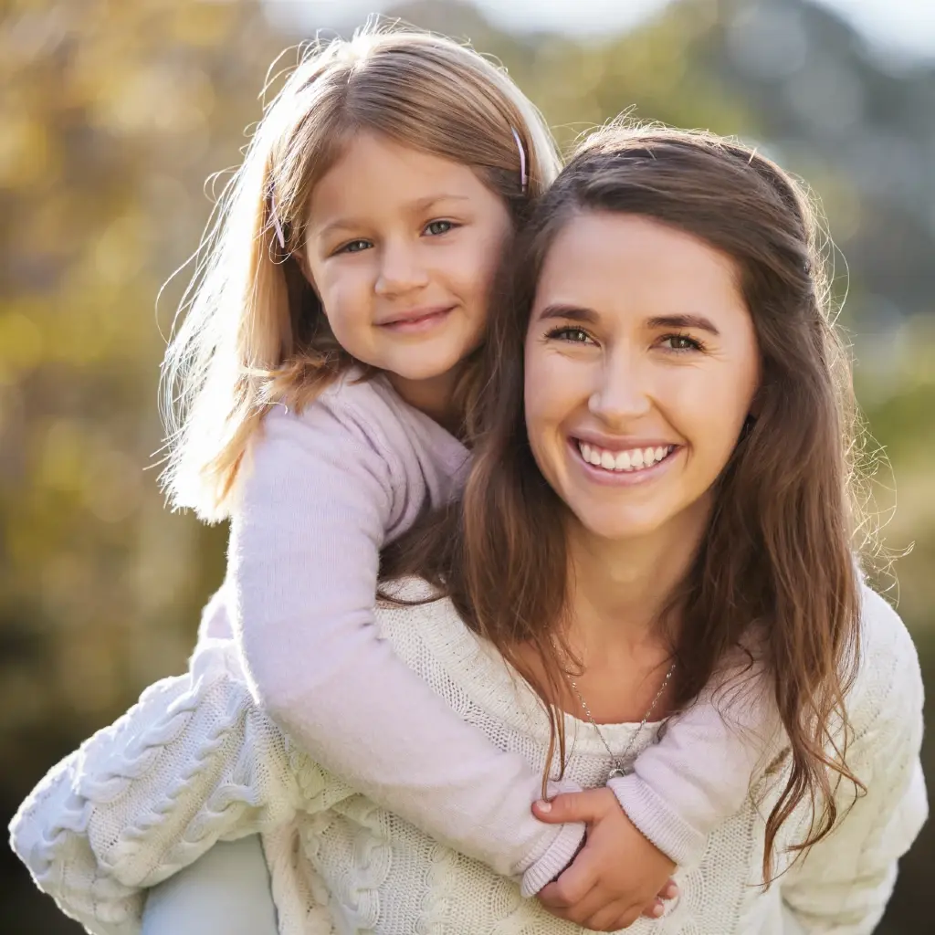 Mom giving her young daughter a piggyback ride.
