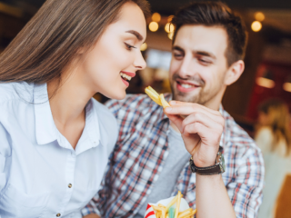 A man feeding a woman french fries.