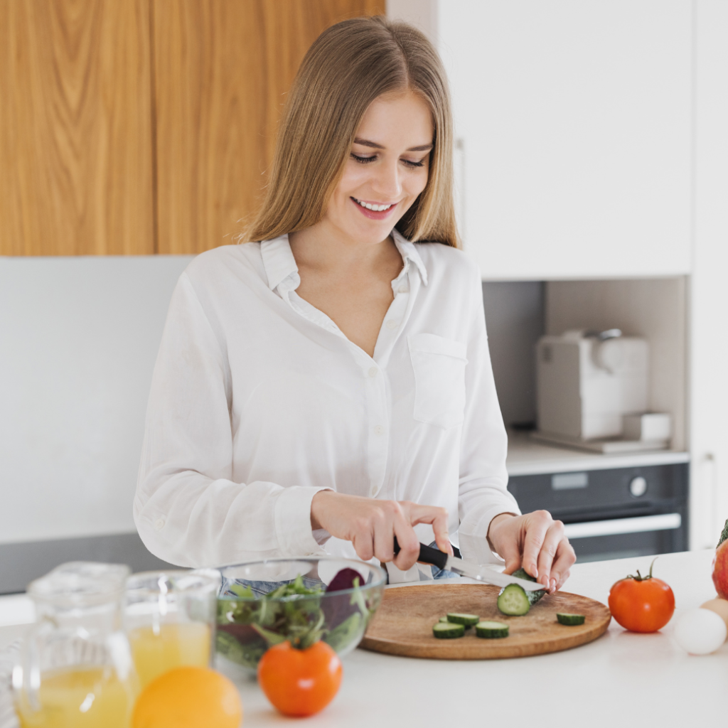 A woman cutting up vegetables in the kitchen.